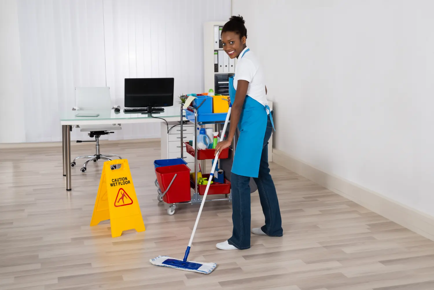 Hausmeisterin wischt den Boden im Büro