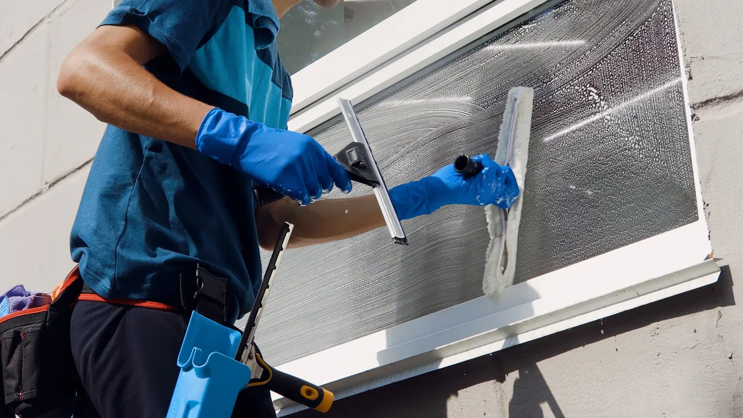 Männlicher professioneller Reinigungsdienstmitarbeiter in Overalls reinigt die Fenster und Schaufenster eines Ladens mit Spezialgeräten